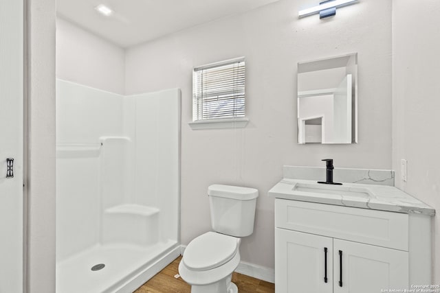 full bathroom with toilet, a stall shower, wood finished floors, baseboards, and vanity