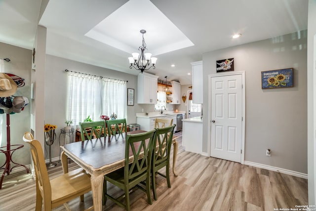 dining space with baseboards, light wood-style flooring, recessed lighting, a raised ceiling, and a chandelier