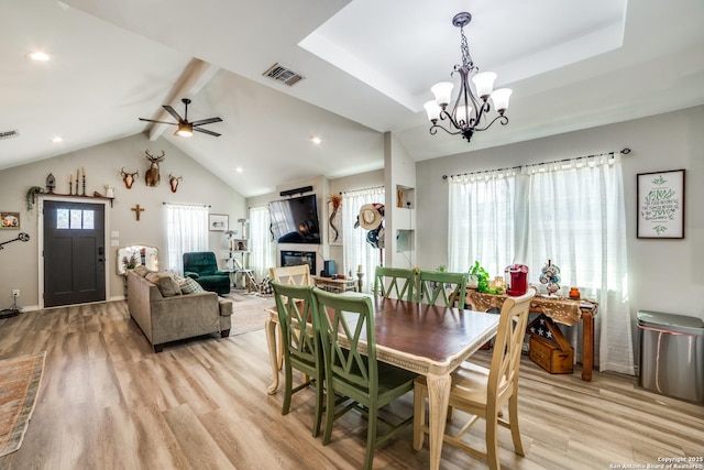 dining room with light wood finished floors, visible vents, lofted ceiling with beams, and a tray ceiling