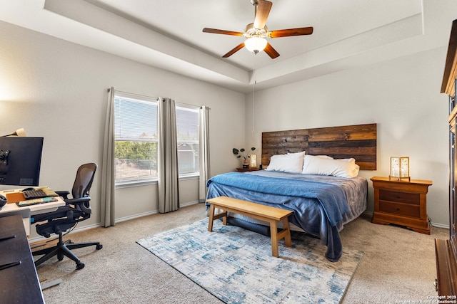 bedroom featuring light colored carpet, a ceiling fan, a raised ceiling, and baseboards