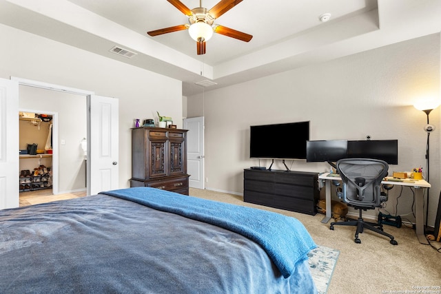 carpeted bedroom with a tray ceiling, baseboards, visible vents, and ceiling fan