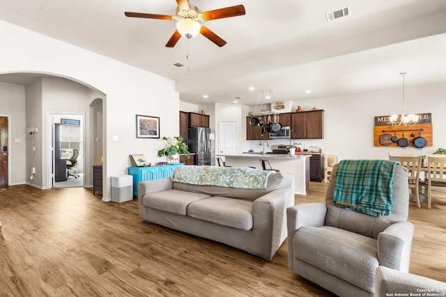 living area with recessed lighting, visible vents, arched walkways, and light wood finished floors