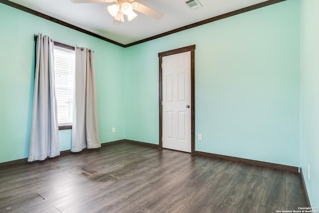 spare room featuring visible vents, dark wood-type flooring, baseboards, ornamental molding, and a ceiling fan