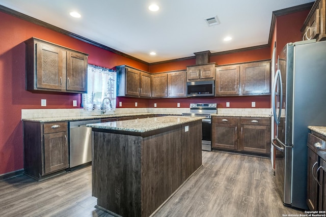 kitchen featuring light wood-type flooring, visible vents, a sink, stainless steel appliances, and crown molding