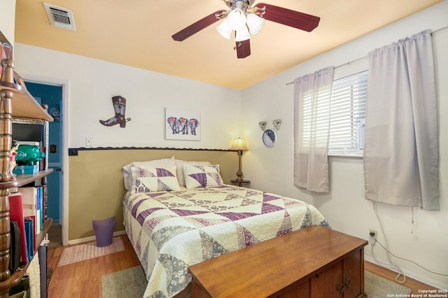 bedroom with a ceiling fan, wood finished floors, visible vents, and baseboards