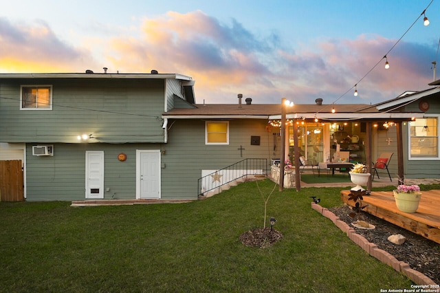 back of house at dusk featuring a lawn and a wall mounted air conditioner