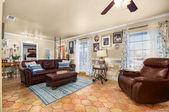 living room with a wealth of natural light, visible vents, wainscoting, and ornamental molding