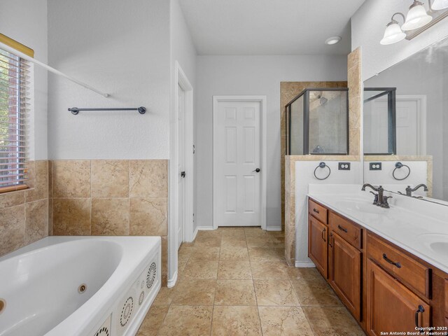 full bath with double vanity, a tub with jets, a stall shower, and a sink