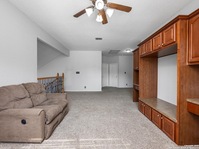 living room with visible vents, carpet, attic access, a textured ceiling, and a ceiling fan