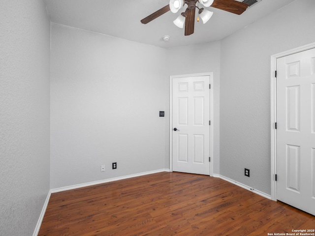 empty room featuring ceiling fan, baseboards, and wood finished floors