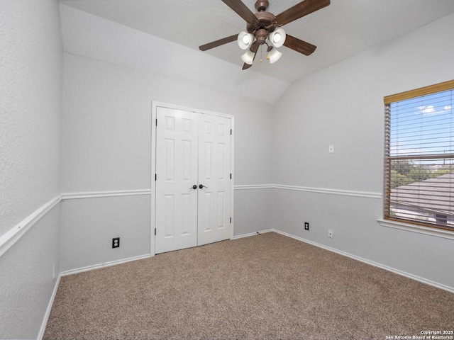 unfurnished bedroom featuring baseboards, carpet floors, a ceiling fan, and vaulted ceiling