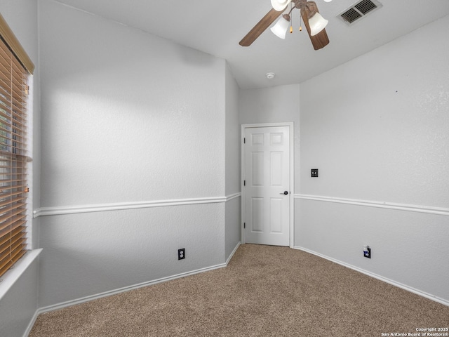 carpeted empty room featuring visible vents, baseboards, and a ceiling fan