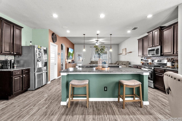 kitchen featuring a kitchen breakfast bar, dark brown cabinets, appliances with stainless steel finishes, and a center island