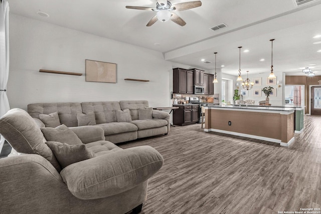 living room featuring recessed lighting, visible vents, ceiling fan with notable chandelier, and wood finished floors