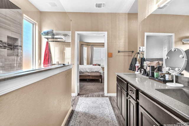 ensuite bathroom with visible vents, a sink, ensuite bath, double vanity, and baseboards