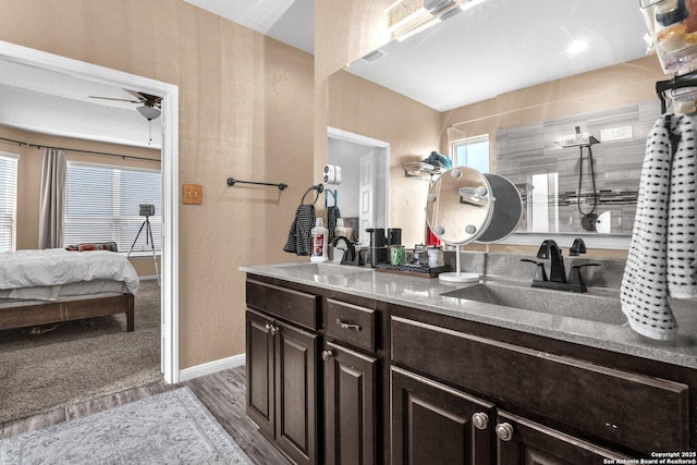 ensuite bathroom featuring a sink, wood finished floors, ensuite bath, and double vanity