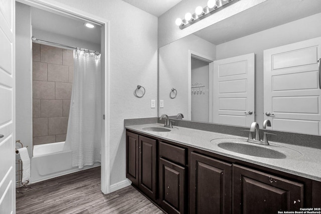 full bathroom featuring double vanity, wood finished floors, shower / tub combo, and a sink