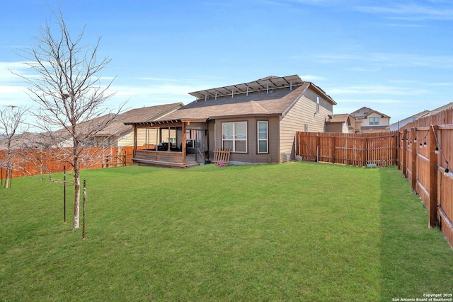 rear view of house featuring a lawn and a fenced backyard