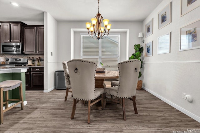 dining room with baseboards, light wood finished floors, and a chandelier