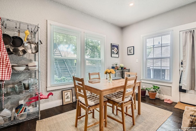 dining space with wood finished floors and a textured wall