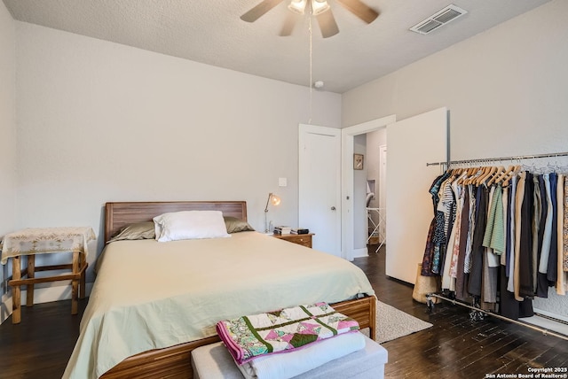 bedroom with a ceiling fan, wood finished floors, visible vents, and a textured ceiling