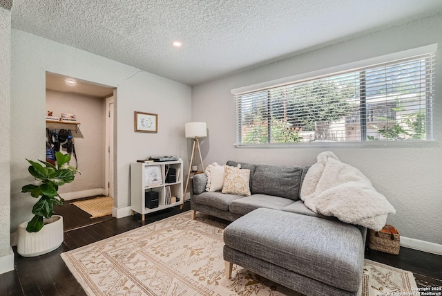 living area with baseboards, a textured ceiling, wood finished floors, and a textured wall