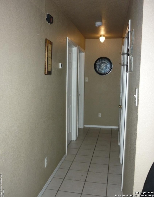 hall with light tile patterned floors and baseboards