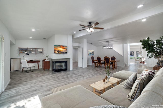 living area featuring vaulted ceiling, recessed lighting, a fireplace, light wood-style floors, and a ceiling fan