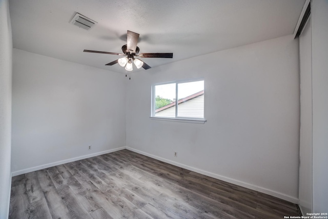 empty room with visible vents, baseboards, wood finished floors, and a ceiling fan