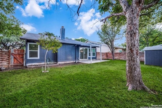 back of house featuring an outbuilding, a lawn, a fenced backyard, a chimney, and a patio area