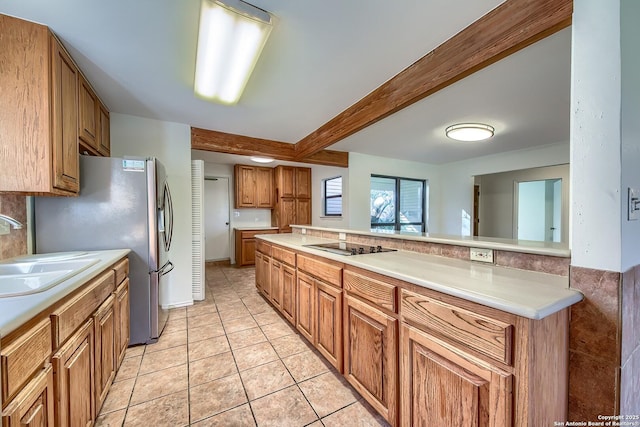 kitchen with beamed ceiling, light countertops, light tile patterned floors, brown cabinets, and a sink