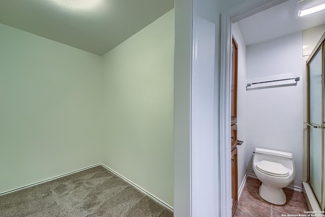 bathroom featuring a shower with door, toilet, and tile patterned floors