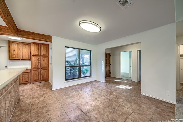 kitchen featuring visible vents, brown cabinets, light tile patterned flooring, light countertops, and baseboards