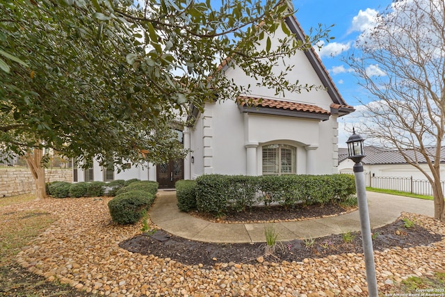 view of front of home featuring a tile roof, fence, and stucco siding