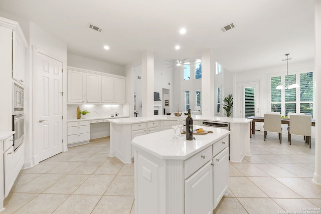 kitchen with a peninsula, light tile patterned flooring, stainless steel appliances, and a kitchen island