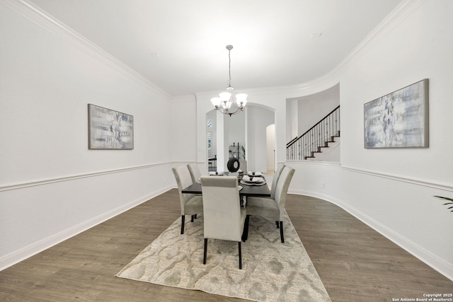 dining space featuring a chandelier, arched walkways, crown molding, and wood finished floors