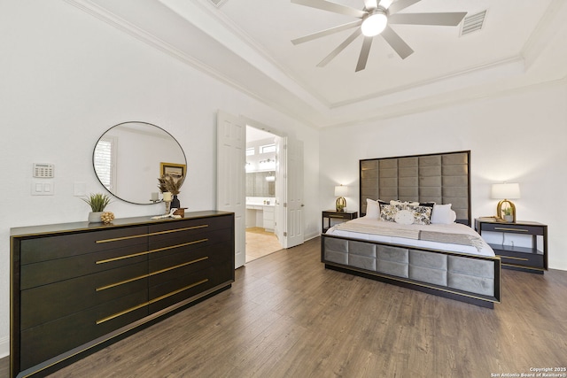 bedroom featuring visible vents, a tray ceiling, dark wood-style flooring, ornamental molding, and ensuite bathroom