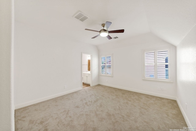 carpeted spare room featuring vaulted ceiling, baseboards, and visible vents