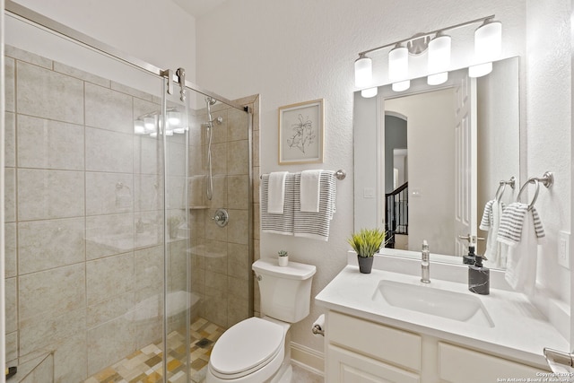 bathroom featuring vanity, a shower stall, and toilet