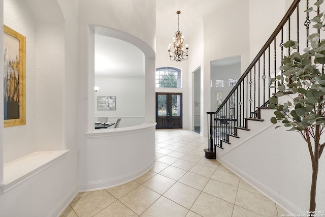 tiled entryway featuring french doors, baseboards, an inviting chandelier, and stairs