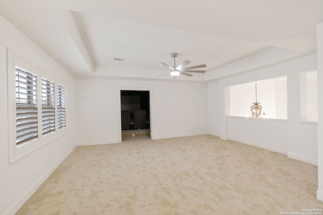 carpeted empty room featuring a tray ceiling and baseboards