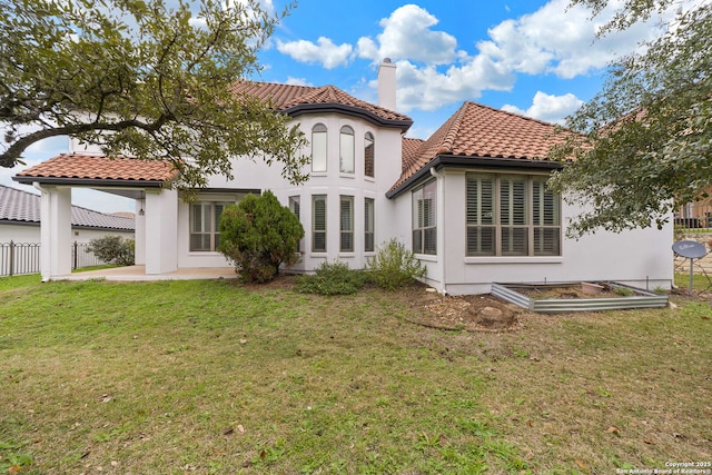 back of property with stucco siding, a tile roof, fence, a yard, and a chimney