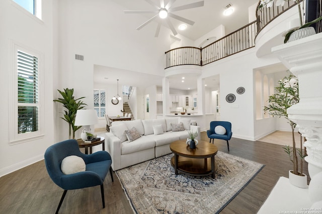 living room with a wealth of natural light, visible vents, stairs, and wood finished floors