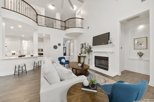 living area featuring a glass covered fireplace, wood finished floors, visible vents, and baseboards