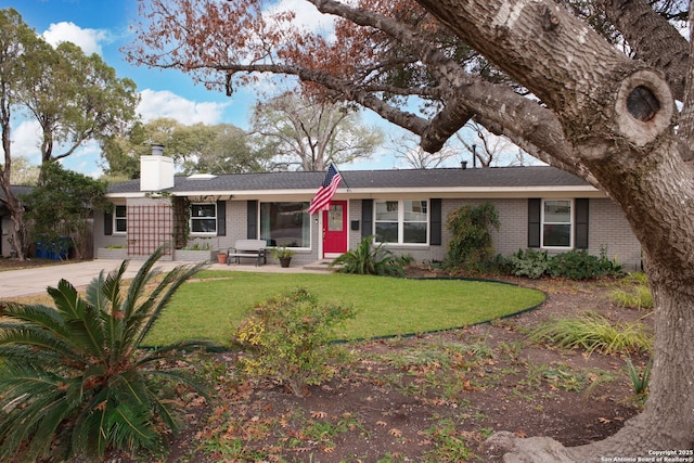 ranch-style house featuring brick siding, a chimney, and a front lawn