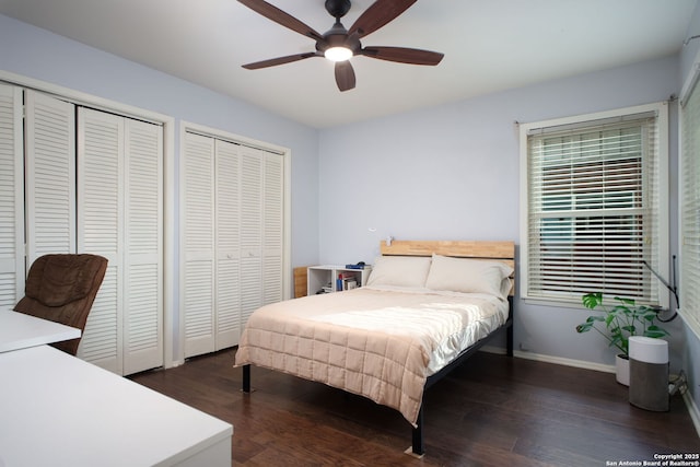 bedroom with a ceiling fan, wood finished floors, multiple closets, and baseboards