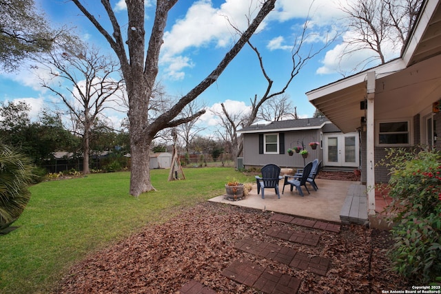 view of yard with a fenced backyard, an outdoor structure, french doors, a fire pit, and a patio area