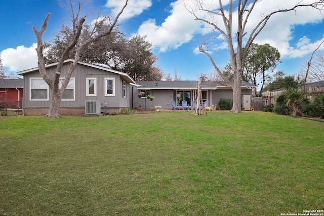 back of property with a lawn, cooling unit, and fence