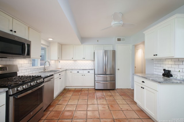 kitchen featuring visible vents, a sink, stainless steel appliances, decorative backsplash, and ceiling fan