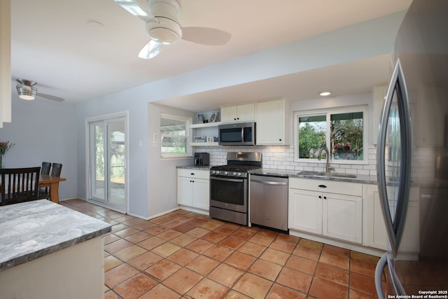 kitchen with a sink, a ceiling fan, backsplash, and stainless steel appliances